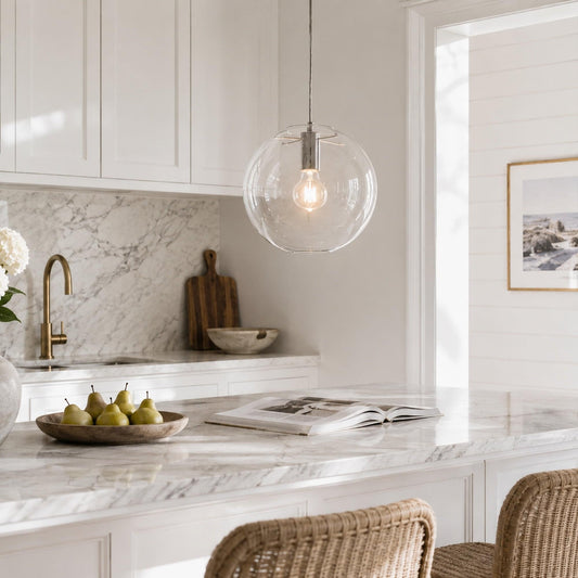 Clear glass globe pendant light with visible bulb glowing in chrome socket