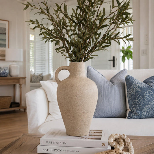 Beige speckled ceramic vase with round side handle, filled with stems