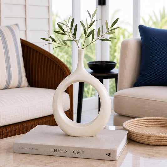 White ceramic vase with circular cutout and greenery stems in the top opening