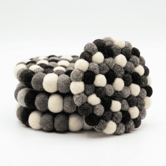 Round wool felt coaster with pebble dot pattern in dark, cream, and gray