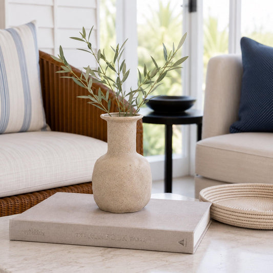 Textured ceramic vase in clay beige, rounded body and narrow neck.