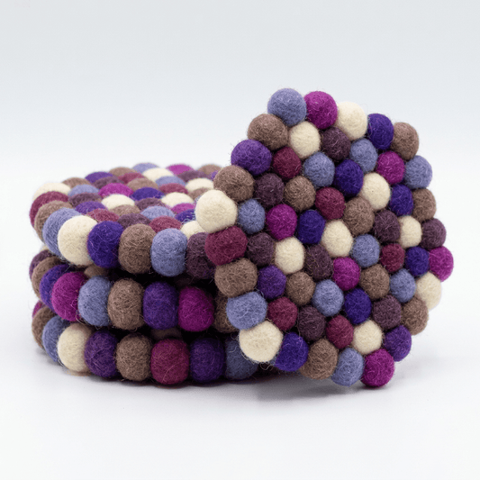 Set of 4 round wool felt coasters with multicolor pom‑pom edges in plum and violet