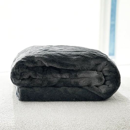 Folded charcoal gray plush throw blanket with thick, cloud-like texture
