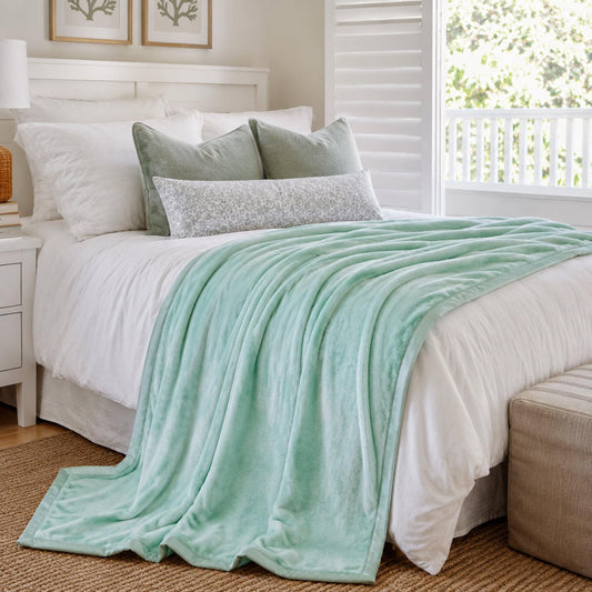 Turquoise plush fur throw blanket draped across a bed, smooth fur surface.