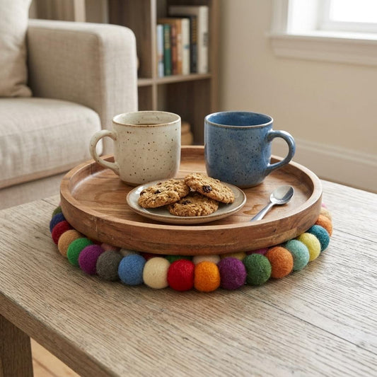 Round wool felt pot mat with multicolor pom-pom trim under coffee cups