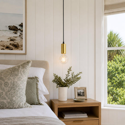 Gold pendant light with clear glass bulb and black cord