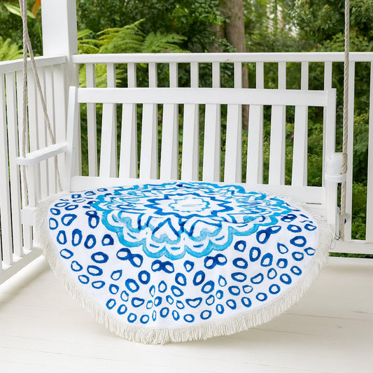 Round picnic blanket in white with blue circular medallion and fringe edge.