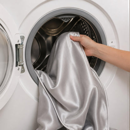 Silver satin quilt cover being placed into a washing machine