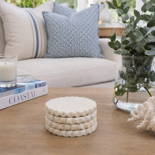 Set of white scalloped marble coasters on a wooden table, round with stacked ridges