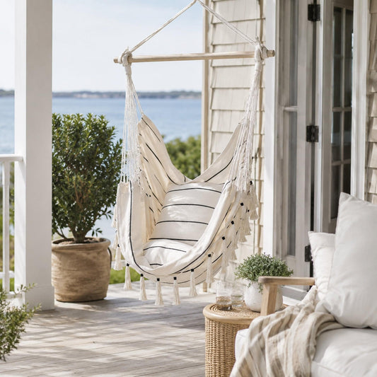 Cream hanging hammock chair with striped cushions and fringe tassels, suspended frame