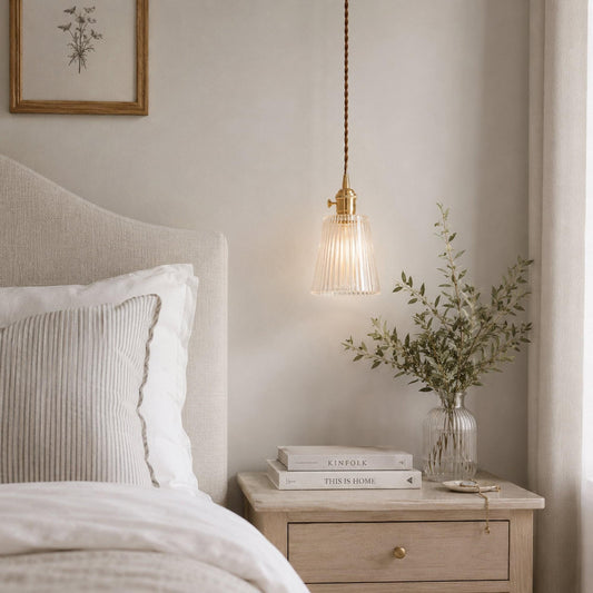 Brass pendant light with clear ribbed glass shade hanging from twisted cord