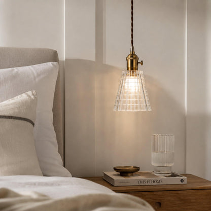 Clear ribbed glass pendant light with antique brass socket on braided cord.