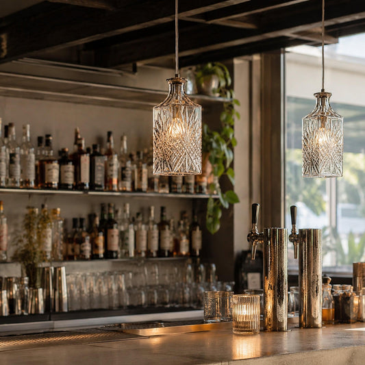 Decanter glass pendant lights with clear etched shades hanging above bar counter