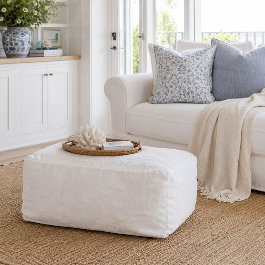 White ottoman in home setting with plush fabric top and low rectangular shape