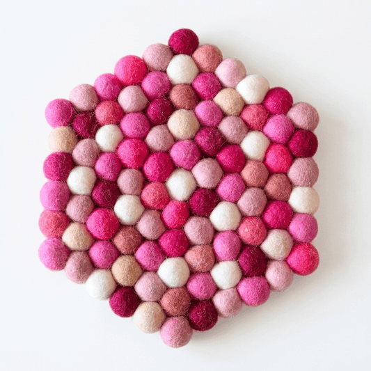 Round wool felt heat mat with pink, berry, and cream pom-poms