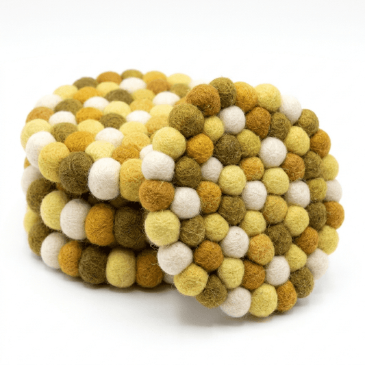 Round wool felt coaster with clustered ball texture in mustard and pale white.