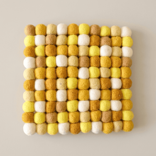 Square wool felt trivet with honey yellow, mustard, tan, and white felt balls